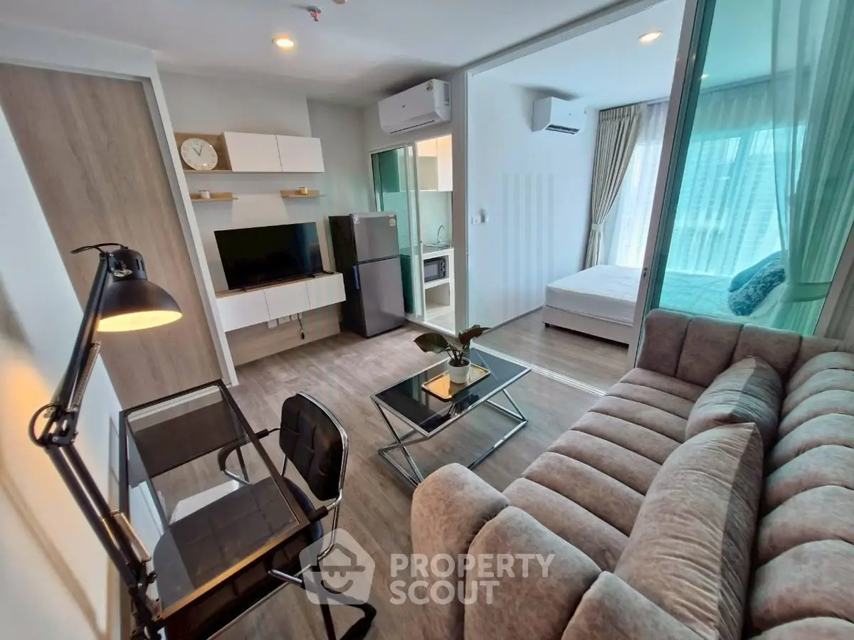 Modern open-plan living room with sleek furniture and a cozy bedroom view, perfect for urban living.