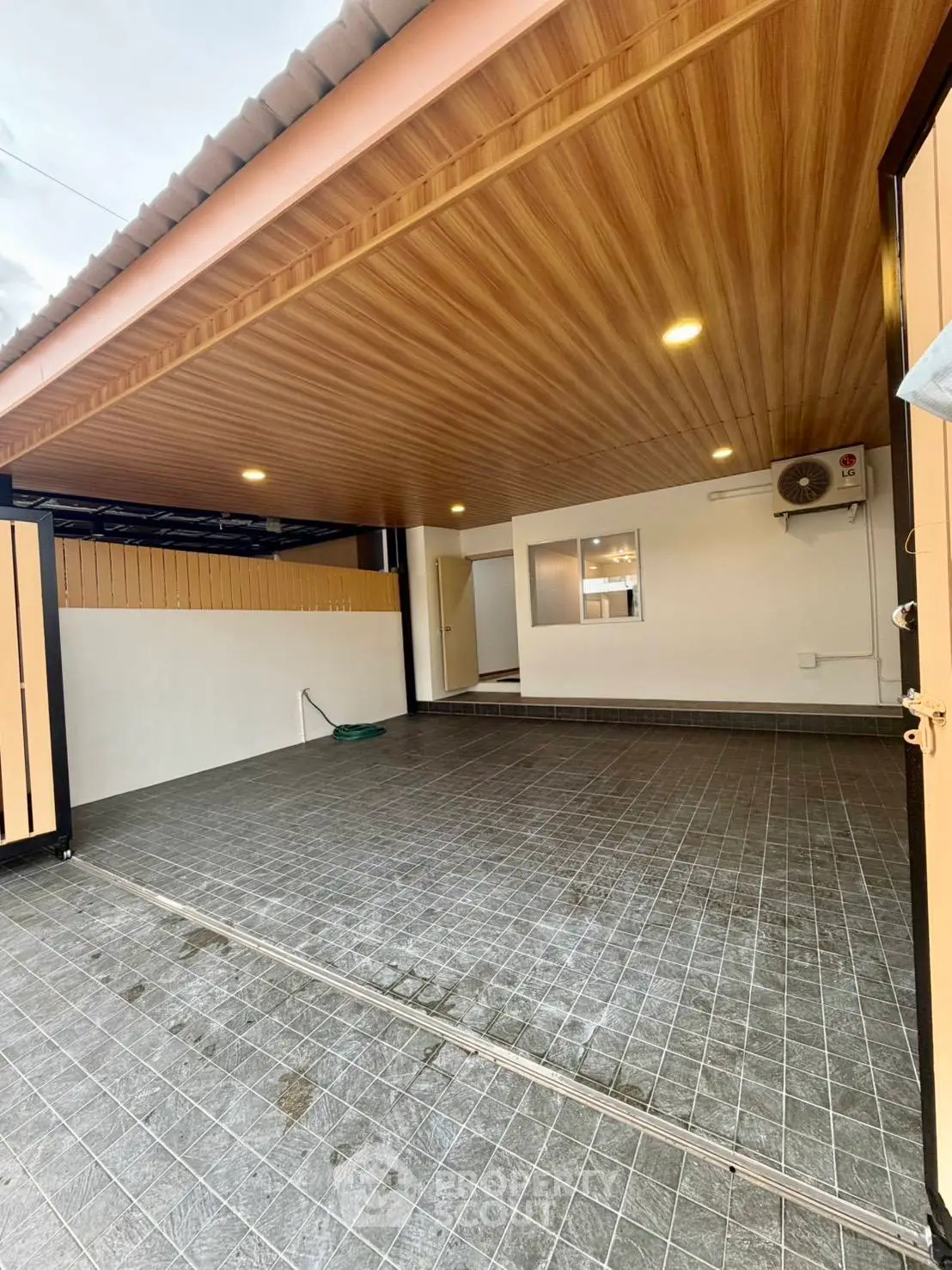 Spacious covered parking area with modern wooden ceiling and tiled floor