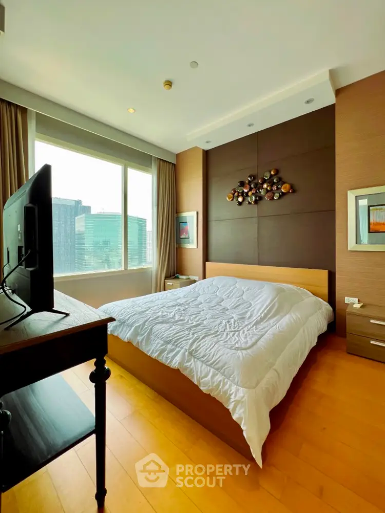 Spacious bedroom with modern decor and large window offering city views.