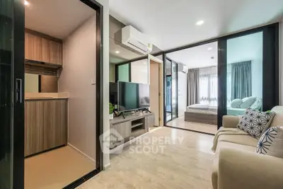 Modern open-plan living room with cozy seating and stylish decor, adjacent to a compact kitchen and bedroom.