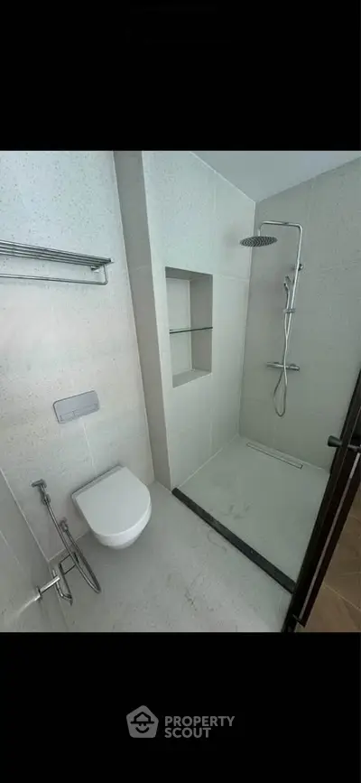 Modern bathroom with sleek shower and wall-mounted toilet in contemporary design.