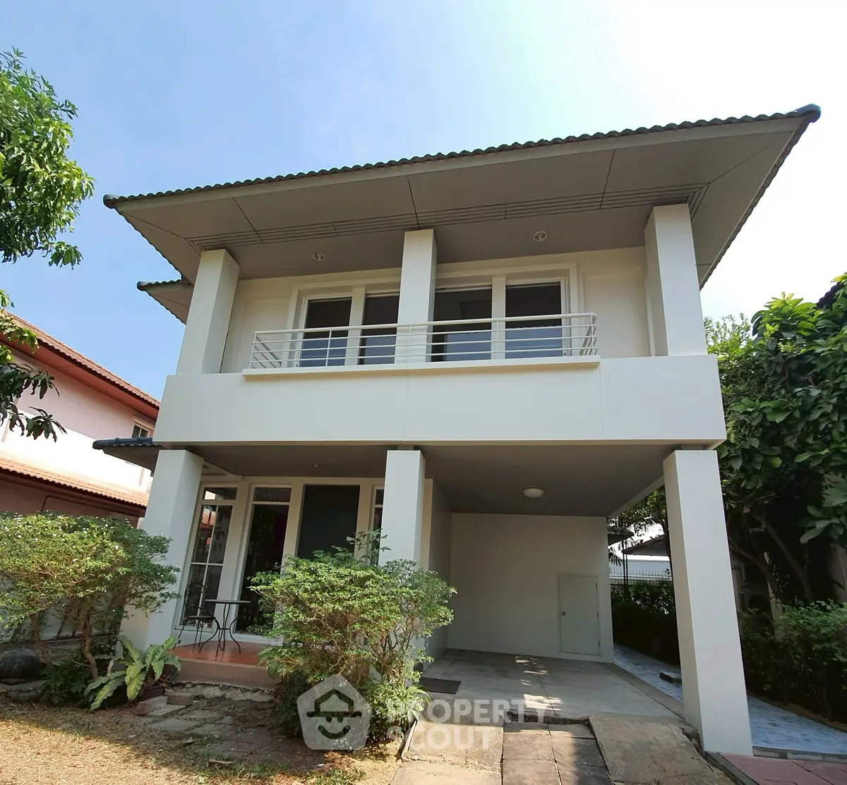 Modern two-story house with spacious balcony and lush greenery