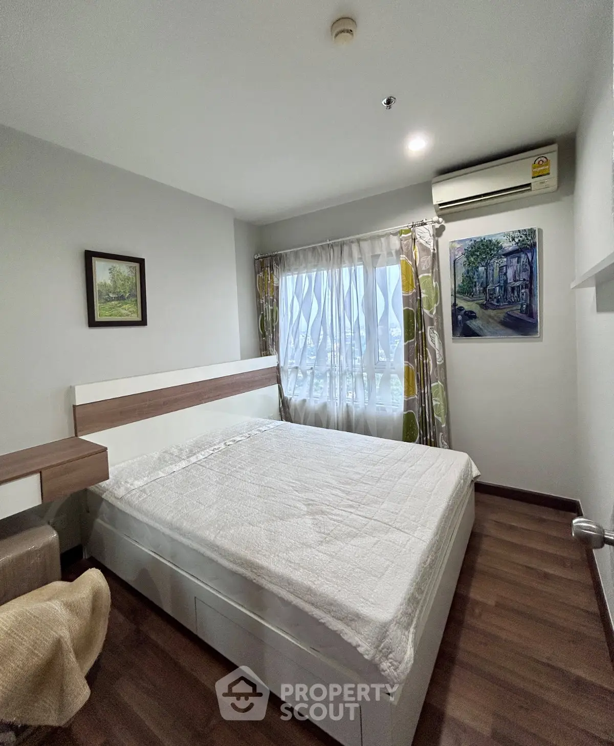 Cozy bedroom with wooden flooring, large window, and modern decor in a stylish apartment.