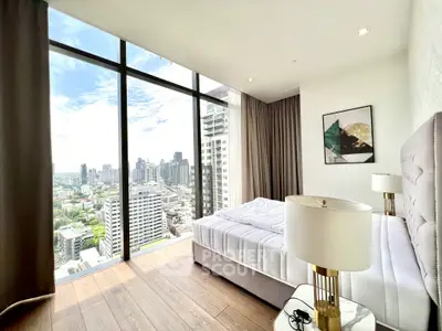 Luxurious bedroom with stunning city view from floor-to-ceiling windows in high-rise apartment.