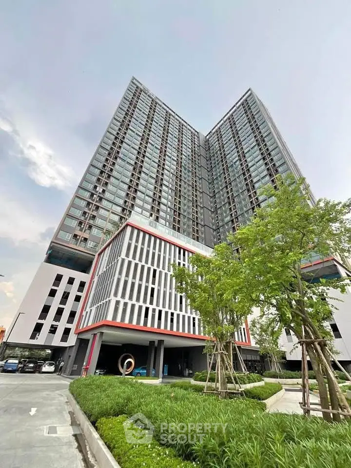 Modern high-rise building with lush landscaping and ample parking space.