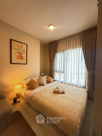 Cozy bedroom with soft lighting and elegant decor, featuring a large window with sheer curtains and a comfortable bed.