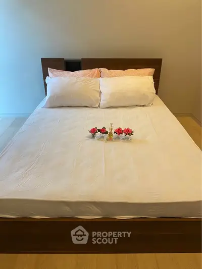Cozy bedroom with a neatly made bed and decorative flowers, perfect for relaxation.