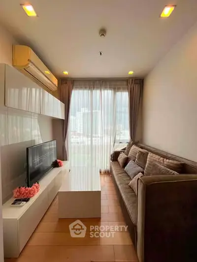 Modern living room with large window and city view, featuring sleek furniture and cozy ambiance.