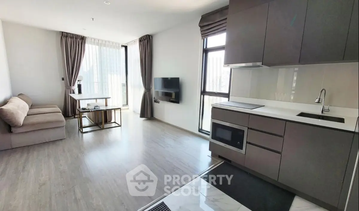 Modern open-plan living room with sleek kitchen and large windows in a high-rise apartment.