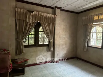Spacious room with tiled flooring and large windows, featuring elegant curtains and natural light.