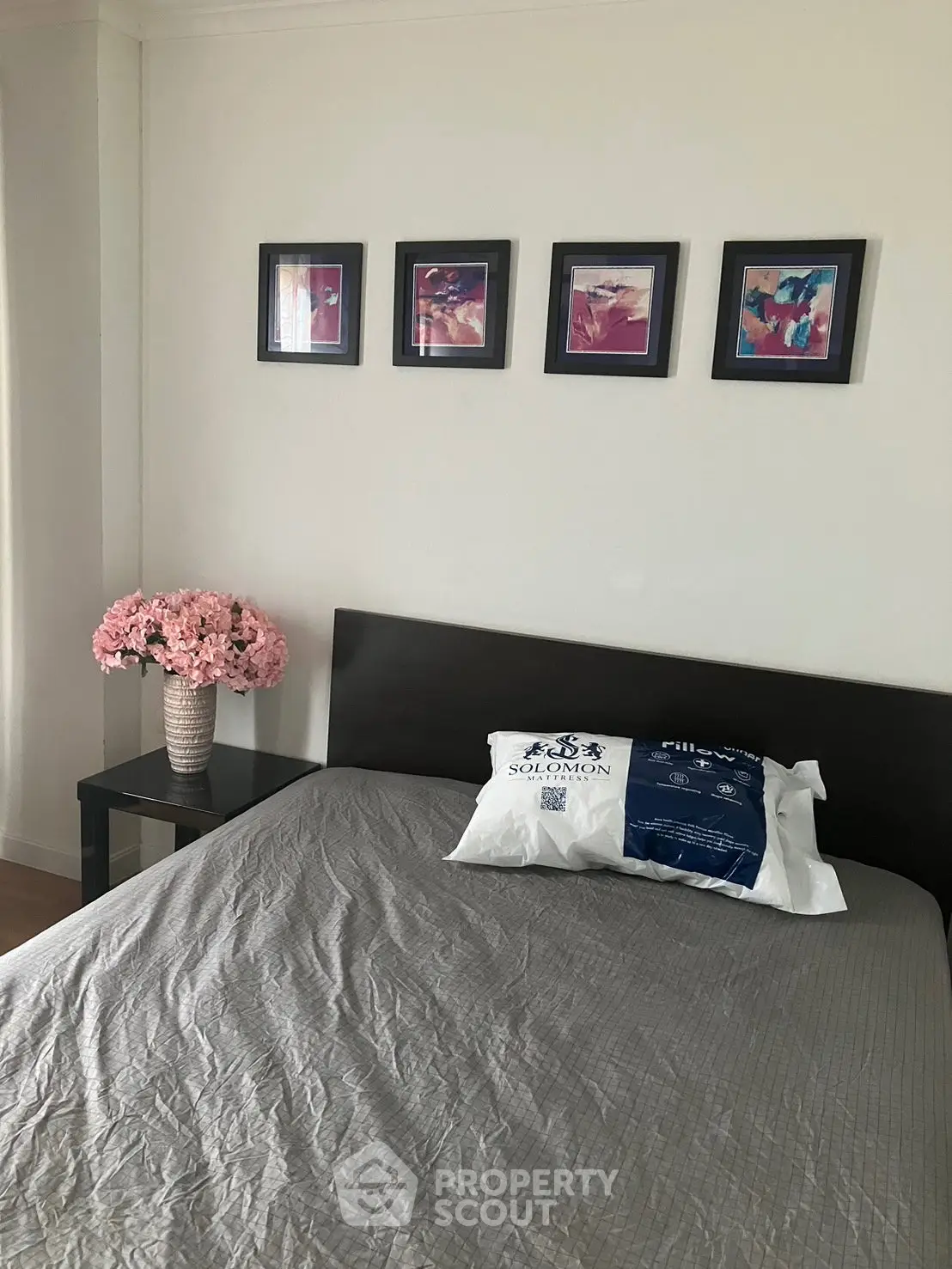 Cozy bedroom with modern decor, featuring a stylish bed, elegant wall art, and a chic side table with flowers.