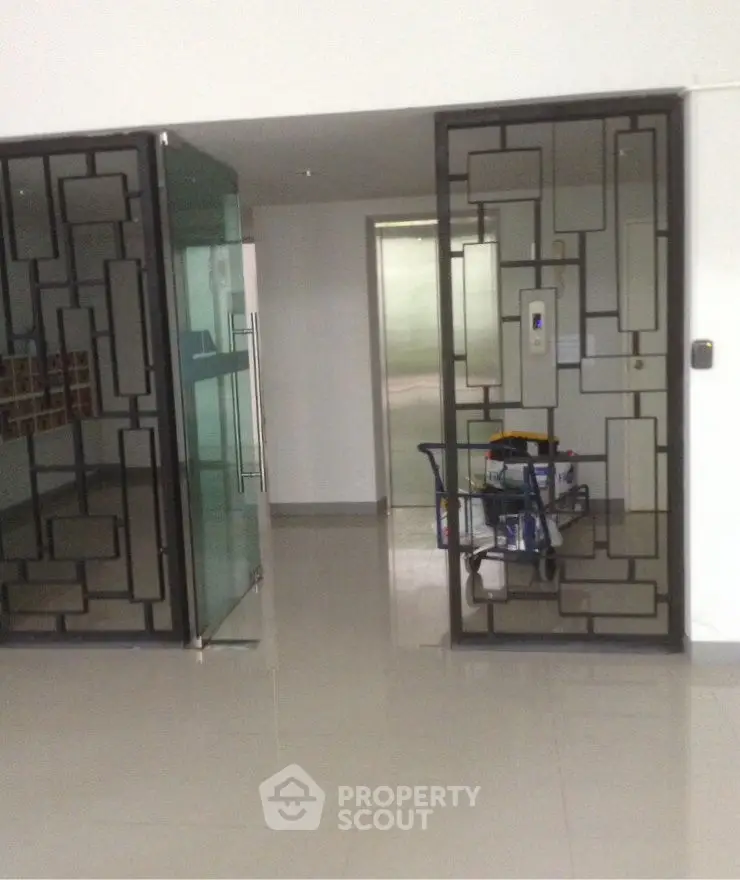Modern building entrance with sleek glass doors and geometric metal design.