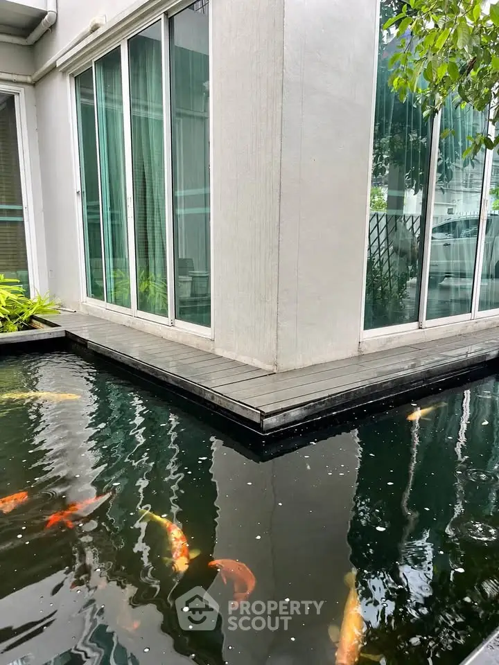 Modern home exterior with elegant koi pond and large glass doors, offering a serene and luxurious ambiance.