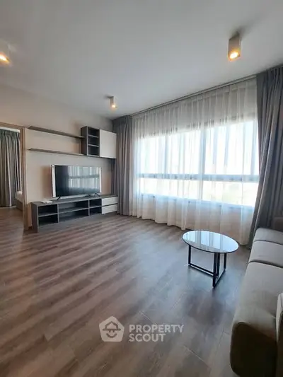 Spacious modern living room with large window and stylish furnishings.