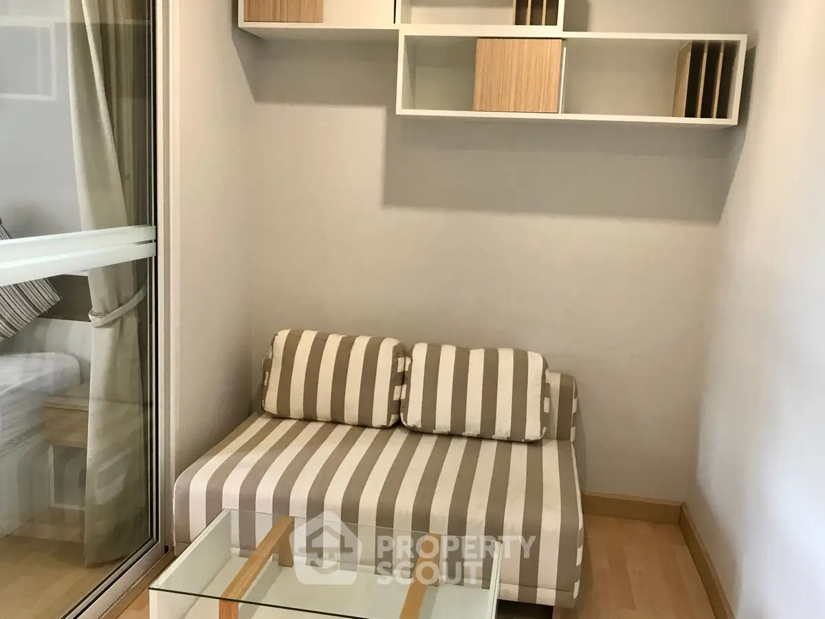 Cozy small living area with striped sofa and glass coffee table, perfect for compact spaces.