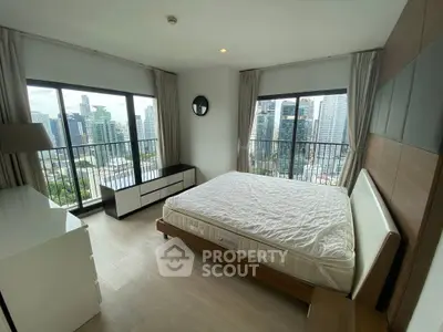 Spacious bedroom with panoramic city views and modern furnishings.