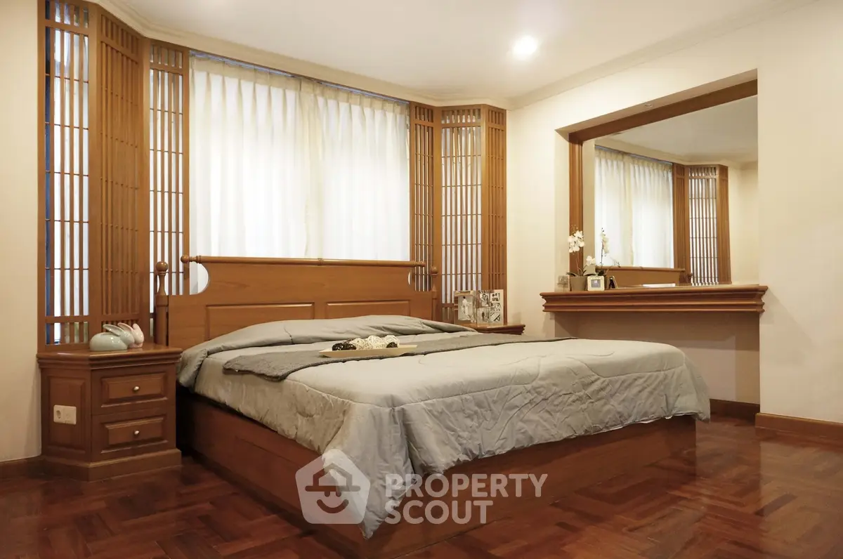 Elegant bedroom with wooden accents and large mirror, perfect for relaxation.