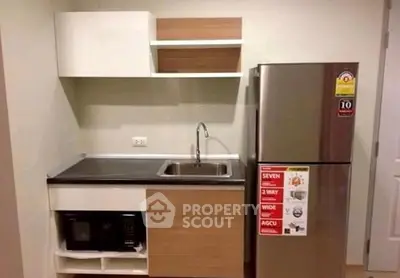 Compact modern kitchen with sleek cabinetry and stainless steel fridge