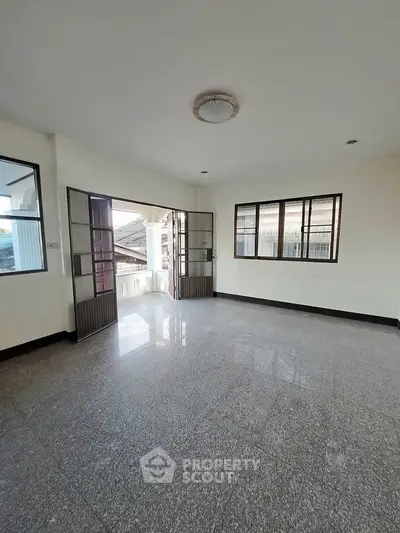 Spacious empty room with large windows and glossy tiled floor, perfect for customization.