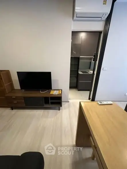 Modern living room with sleek furniture and open kitchen view, featuring air conditioning.