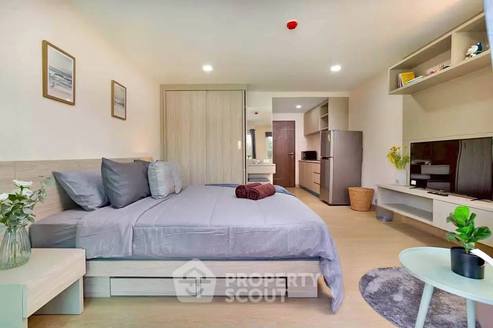 Modern bedroom with sleek design, featuring a cozy bed, stylish decor, and a compact kitchen area.