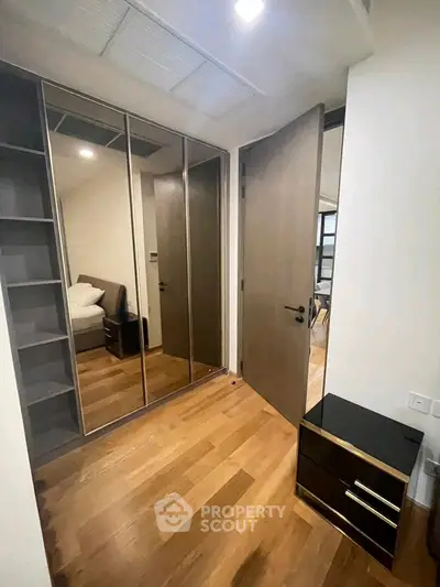 Modern bedroom with mirrored wardrobe and wooden flooring