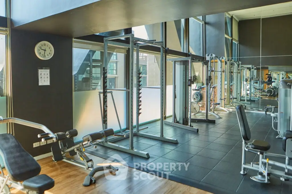 Spacious modern gym with state-of-the-art equipment and large windows for natural light.
