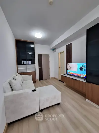 Modern living room with sleek design, featuring a cozy white sofa and a flat-screen TV on a wooden stand.
