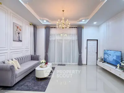 Elegant living room with chandelier, modern sofa, and large TV in a stylishly decorated home.