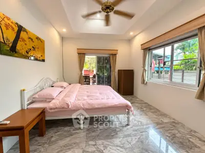 Spacious bedroom with elegant decor and large windows offering garden views