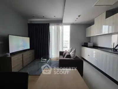 Modern living room with sleek kitchen, large TV, and cozy sofa in a stylish apartment.