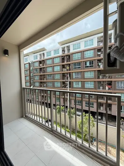 Spacious balcony with a view of modern apartment complex, perfect for relaxation and enjoying the outdoors.