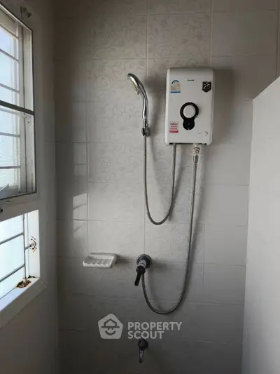 Modern bathroom with shower and water heater, featuring elegant tile design.