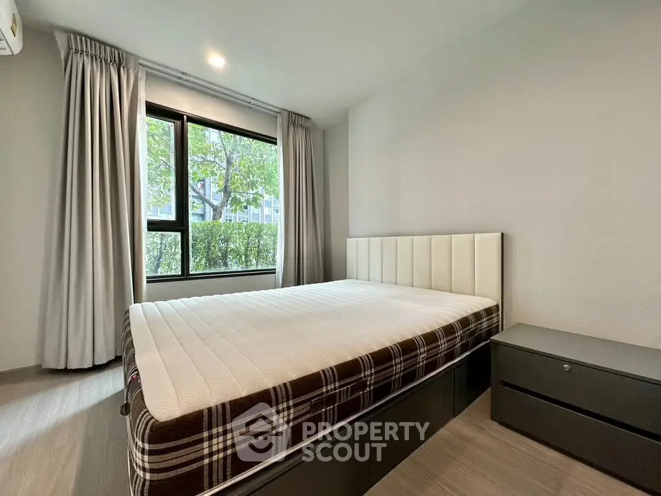 Modern bedroom with large window and stylish bed in a serene setting.