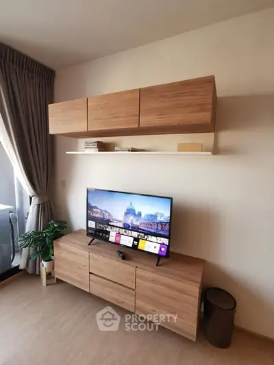 Modern living room with sleek wooden TV cabinet and wall-mounted shelves, featuring a large window with curtains.