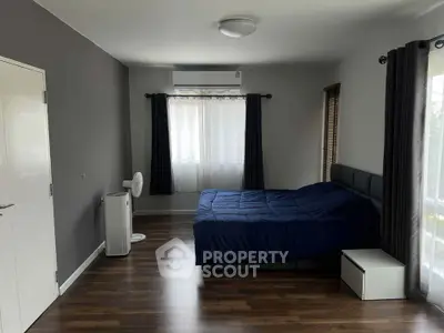 Spacious bedroom with modern decor and large windows for natural light.