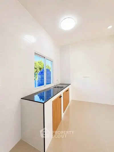 Modern minimalist kitchen with sleek countertops and ample natural light.