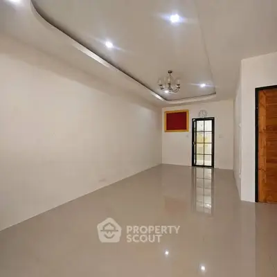 Spacious empty living room with modern ceiling lights and elegant flooring.