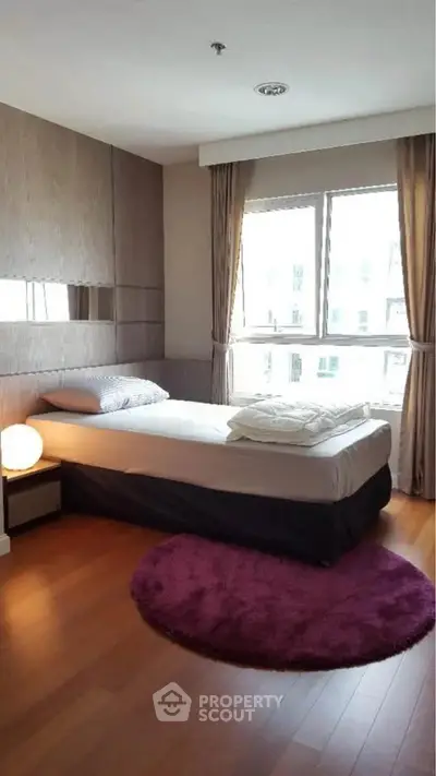 Cozy bedroom with large window and modern decor, featuring a plush bed and stylish curtains.