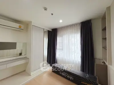 Modern bedroom with large window and built-in storage in a stylish apartment.