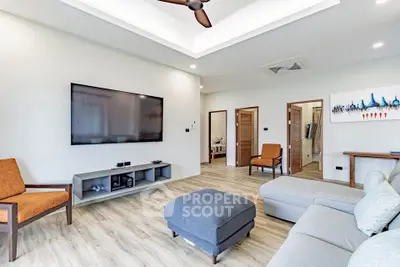 Spacious modern living room with stylish furniture and large TV, perfect for relaxation and entertainment.