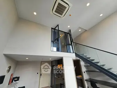 Modern loft apartment with high ceilings and sleek staircase, featuring an open layout and stylish lighting.