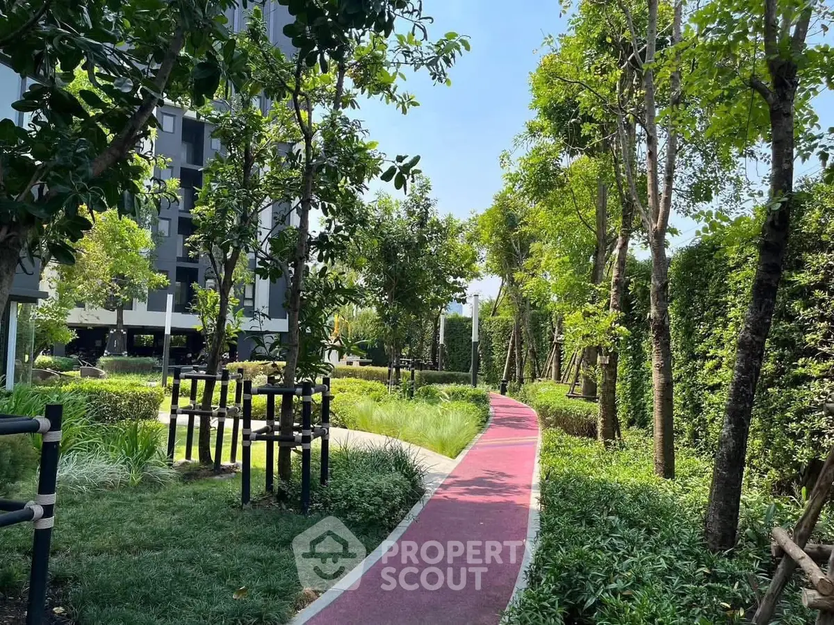 Lush garden pathway in modern residential complex with vibrant greenery and serene atmosphere.