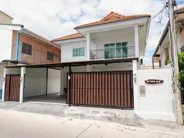 Charming two-story house with gated parking and balcony in a suburban neighborhood.
