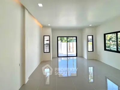 Spacious modern living room with large windows and glossy tiled floor, offering abundant natural light.