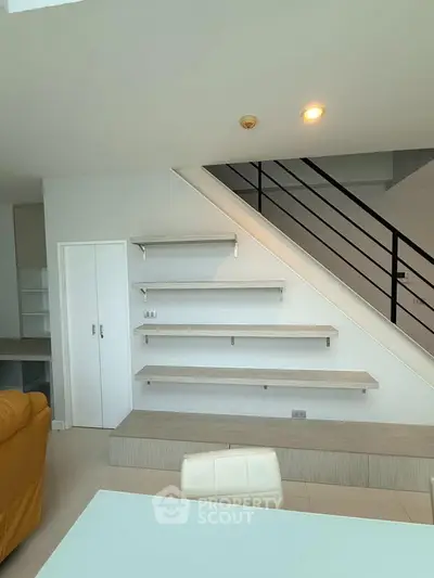 Modern duplex interior with stylish staircase and built-in shelving, perfect for contemporary living.