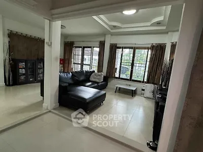 Spacious living room with modern black leather sofa and large windows offering natural light.