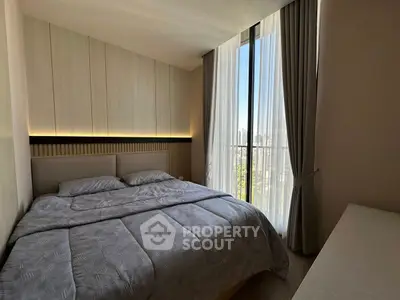 Modern bedroom with large window and stylish decor in a high-rise apartment.