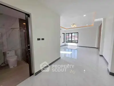 Spacious modern interior with glossy floors and large windows, featuring a bathroom and open living area.