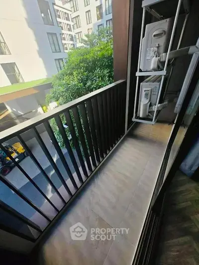 Charming balcony with modern railing and lush greenery view in urban apartment setting.